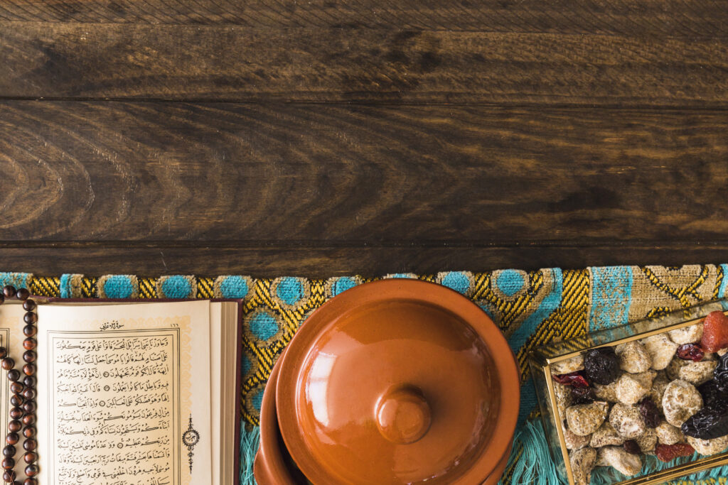 A picture of prayer beads, a prayer rug, a Quran, and sweets