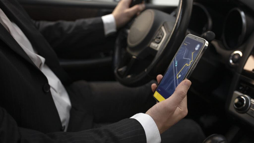 A driver holding a phone with location tracking