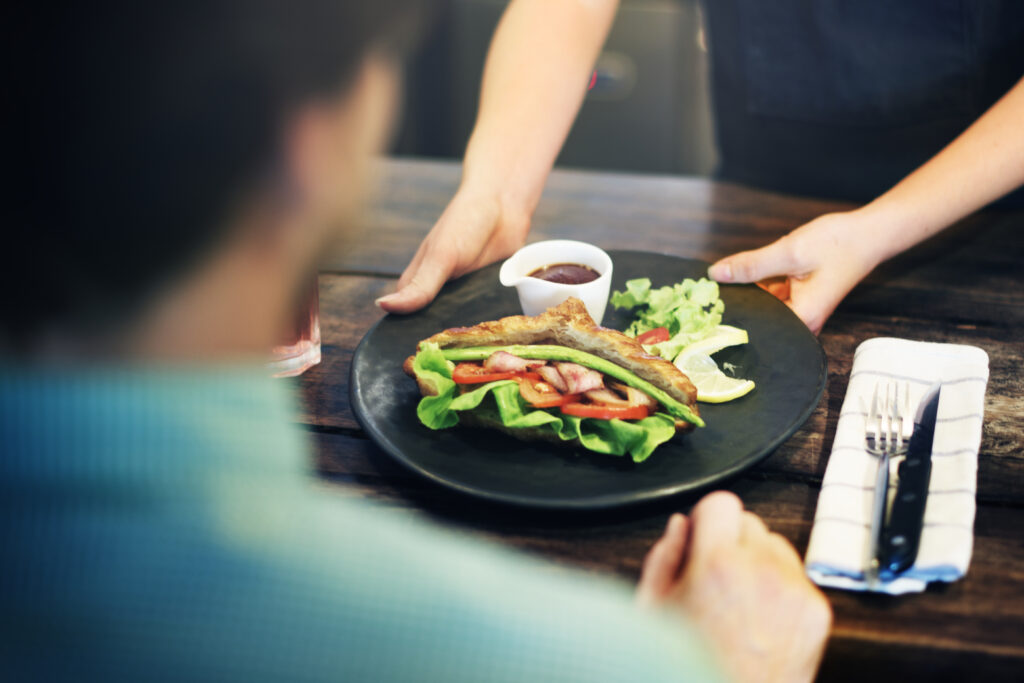 A waiter serving food with his right hand and this reflects Malaysian food etiquette