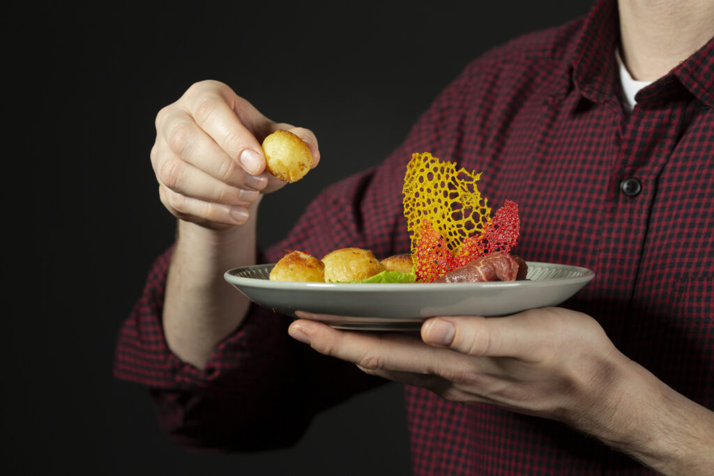 A person holding a plate of food, eating with their right hand in Malaysian food etiquette